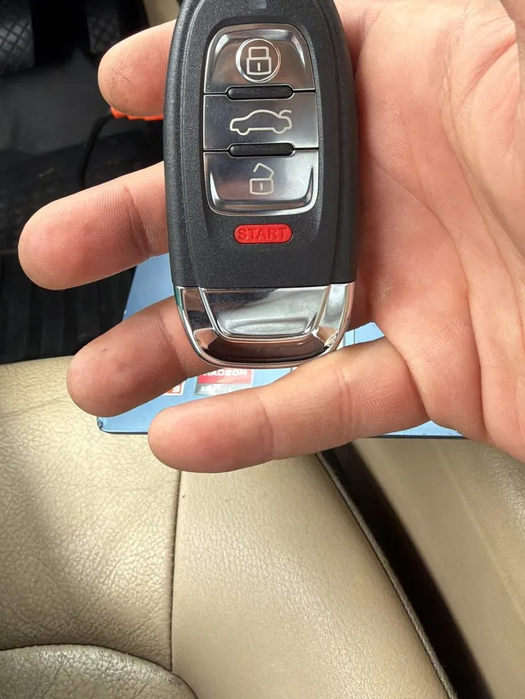 An Audi smart key held in front of the laptop used to program it