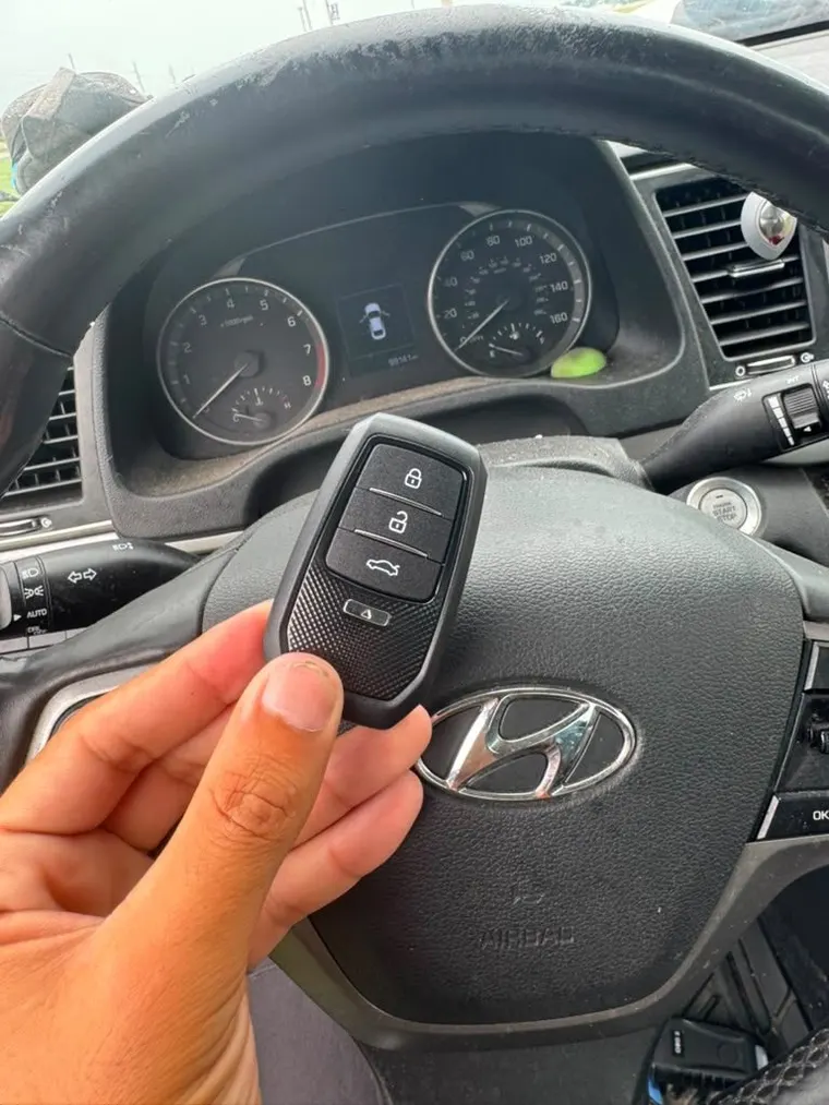 A new Hyundai remote key held at the steering wheel of the car