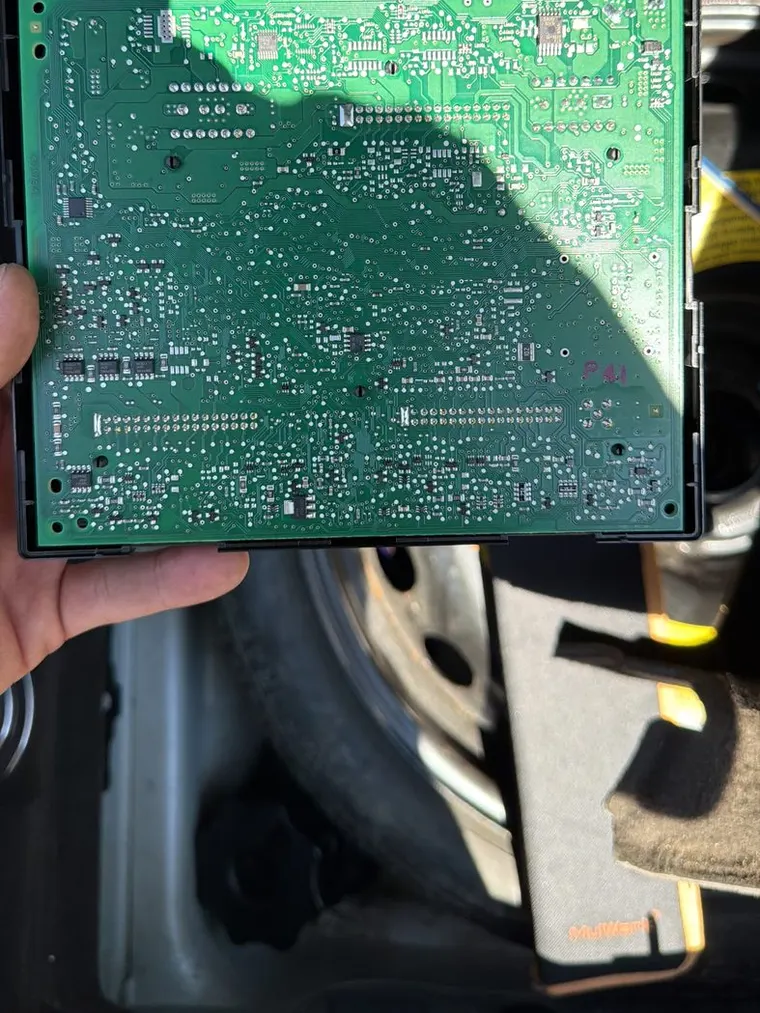 A vehicle control module circuit board held in a gloveless hand