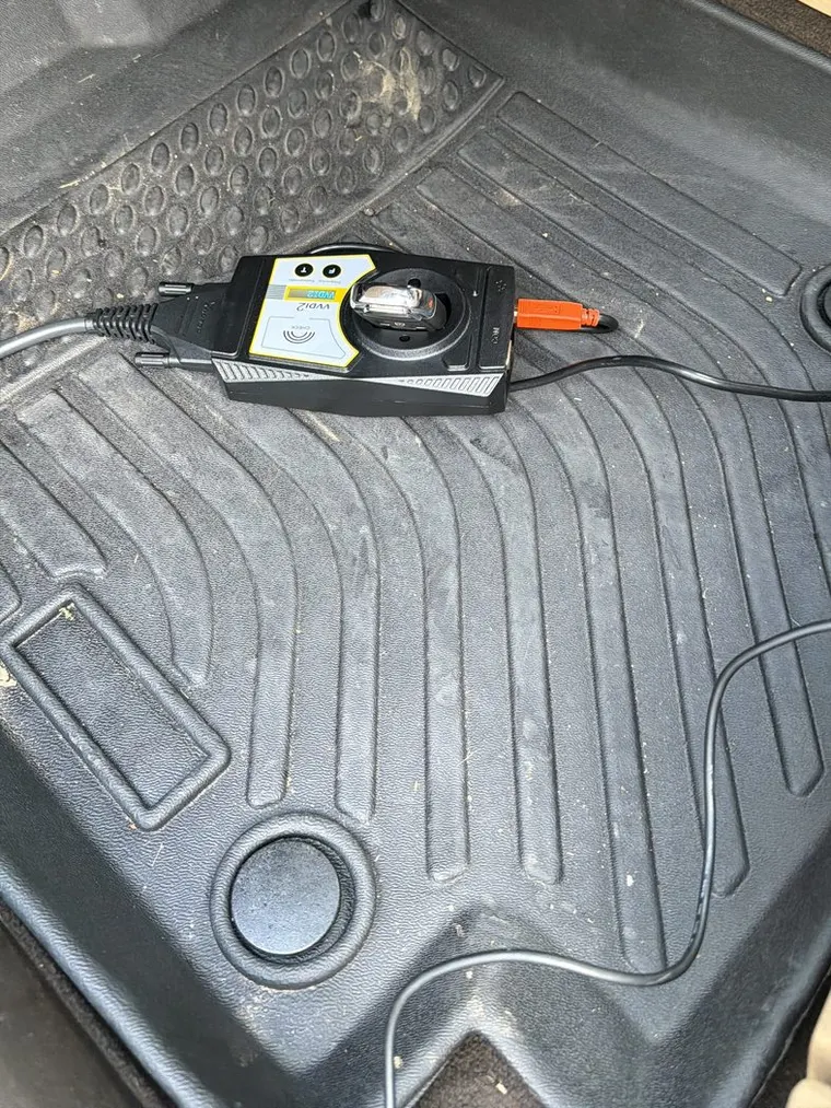 A key programmer plugged in and running inside a vehicle