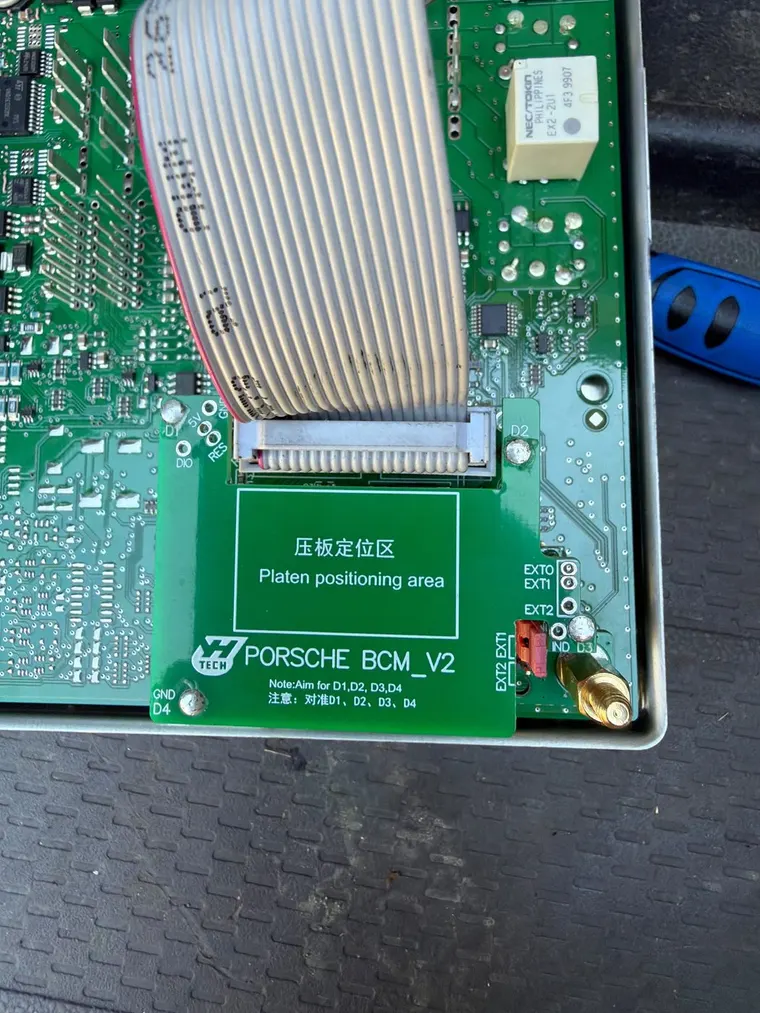 A Porsche body control module mounted on a programming adapter