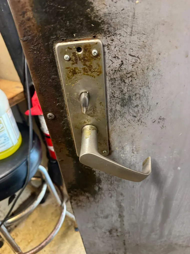 A commercial lever lock fitted to a worn steel service door