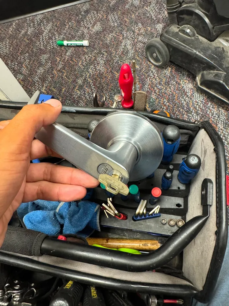 A commercial lever handle and its new key held in one hand