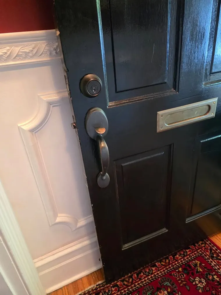 A black front door with refitted lock hardware and a mail slot
